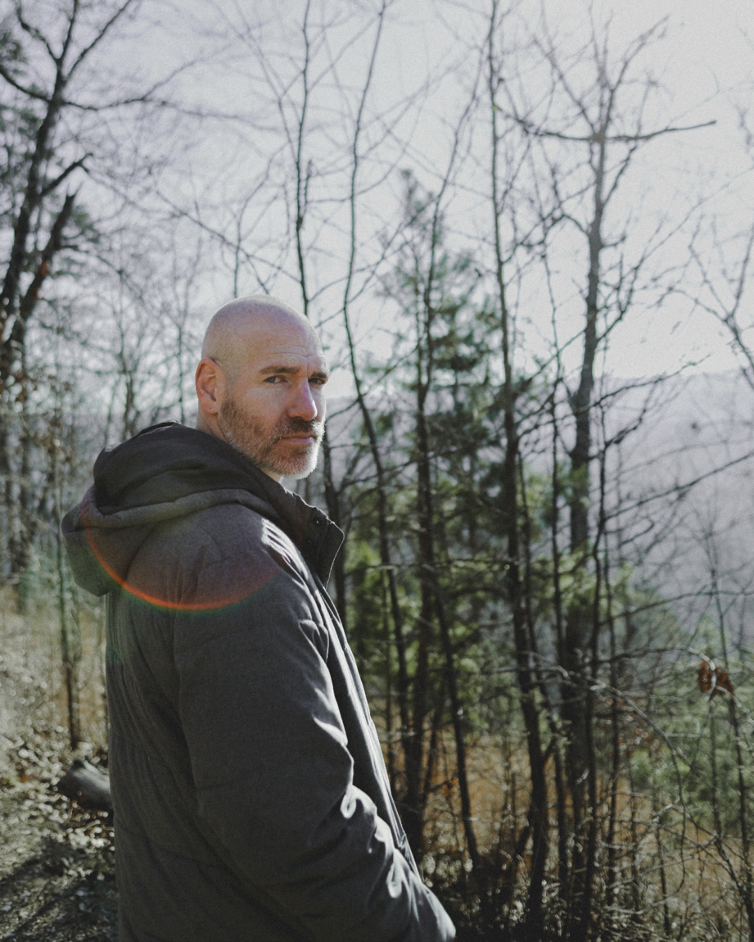 Kevin Capehart standing among bare winter trees at golden hour